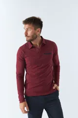 Polo de manga larga negra con cuello clásico, tapeta de dos botones y bolsillo de parche en el pecho con ribete blanco. Logo de la marca bordado en blanco sobre el bolsillo.