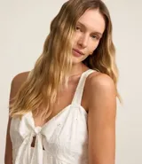 Blusa blanca sin mangas confeccionada en laise con escote corazón, lazo en el busto, tirantes medianos con elásticos, lastex en la espalda y bordados.