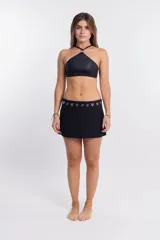 Top de bikini negro con cuello halter, confeccionado en tela brillante. El cuello se une en el centro con una argolla metálica plateada.