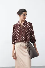 Camisa de manga larga color marrón con estampado de lunares blancos, confeccionada en tejido liviano con cuello clásico y botones frontales.