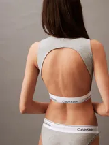 Conjunto Calvin Klein Modern Cotton color gris melange, compuesto por un corpiño deportivo sin mangas y una bombacha tipo tanga, ambos con banda elástica blanca con logo de la marca.