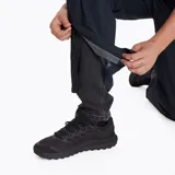 Pantalón impermeable Merrell Hardshell negro, con cintura elástica, diseño holgado, apertura lateral con cierre para acceder a los bolsillos del pantalón inferior, logo reflectante, ajuste en la parte inferior con cierre y botón snap, y bolsa para guardarlo.