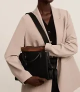 Cartera satchel negra de material sintético con textura diagonal, doble asa de mano y asa larga removible de gross. Incluye porta monedas y cierre por cremallera.