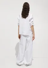 Camisa verde de lino con cuello camisero, manga larga con puños abotonados, bolsillo de parche en el pecho y cierre frontal con botones.