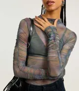 Blusa de tule con cuello alto y mangas largas con fruncido lateral.