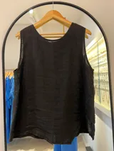 Musculosa negra de tejido ligero, posiblemente lino o una mezcla similar, con escote redondo en la espalda y corte holgado.