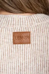 Chaleco de punto oversize con escote en V, hombros caídos y textura acanalada en color beige, confeccionado en una mezcla de acrílico, poliéster, nylon, lana y spandex.