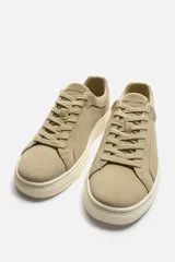 Zapatillas bajas color beige de piel serraje con cordones y suela plana color crema.