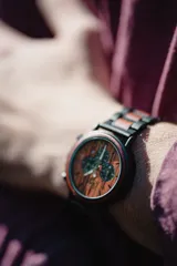 Reloj multifuncional para hombre, con caja de madera de sándalo rojo y acero inoxidable negro. La esfera es de madera de sándalo rojo con subdiales negros funcionales que ofrecen cronógrafo, indicador de 24 horas y fechador. La malla es de acero inoxidable negro con incrustaciones de madera de sándalo rojo.