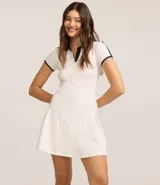 Vestido corto de mujer, estilo skater, color verde oscuro con cuello polo y ribetes blancos en el cuello, puños y hombros. Presenta un escote en V y mangas cortas.