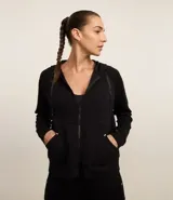 Campera deportiva gris confeccionada en microfibra, con capucha con cordón, cierre delantero, bolsillos y mangas largas.