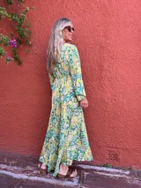Vestido largo de seda con escote en V y mangas largas amplias. Presenta un estampado tipo cachemir o mandala en tonos verde, amarillo y blanco/crudo.