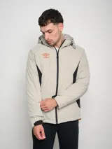 Campera corta de abrigo Umbro Crafted Pro, color negro con paneles laterales en gris. Presenta capucha con cordón ajustable, cierre frontal completo y logo de la marca bordado en el pecho.