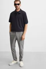 Pantalón negro de corte slim fit, confeccionado en tejido elástico. Cuenta con cintura elástica, bolsillos frontales y traseros de vivo. Cierre frontal con cremallera y botón.