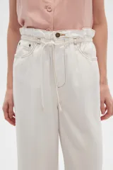 Pantalón de jean color beige, de tiro alto, corte palazzo y estilo paper bag.