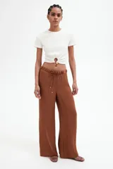 Pantalón palazzo color marrón con cintura elástica y cordón ajustable con cuentas decorativas. Tiene bolsillos laterales discretos.