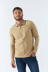 Chomba manga larga color beige con rayas horizontales blancas, cuello polo con borde azul marino y logo bordado en el pecho.