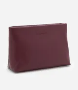 Neceser de poliuretano color borgoña, con forma trapezoidal y cierre de cremallera.