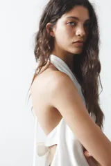 Top negro de satén con cuello halter drapeado ajustable con lazada en el cuello y espalda descubierta con lazada.