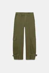Pantalón cargo de mujer color verde militar, tiro medio, corte ancho y recto (barrel). Presenta bolsillos laterales y bolsillos de plastrón con solapa en las piernas. El bajo es ajustable con trabillas y hebillas metálicas.