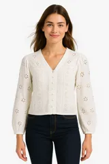 Camisa blanca de algodón con bordado tipo broderie, corte al cuerpo, cuello en V y cierre frontal con botones.
