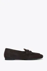 Zapato mocasín de mujer color marrón oscuro, confeccionado en serraje con detalle de tira en la parte delantera y acabado en punta redonda.