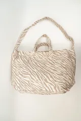 Bolso tipo tote bag con estampado de cebra en tonos beige y blanco. Tiene doble asa corta y correa larga para colgar del hombro.