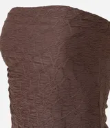 Top tipo bandeau sin breteles, color marrón oscuro, confeccionado en tejido de malla texturizada con efecto arrugado y un ruedo asimétrico y alargado en un lateral.