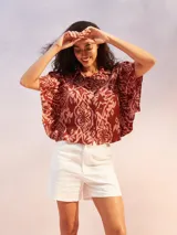 Camisa marrón con estampado abstracto en tonos rosados, de corte holgado, cuello camisero y mangas cortas amplias.