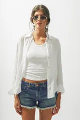 Camisa blanca de lino de manga larga con cuello clásico y cierre frontal con botones.