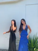 Vestido largo con escote en V, estampado en tonos rojizos y rosados, con un patrón ondulado. Presenta cut-outs laterales bajo el busto y breteles finos que se cruzan en la espalda.