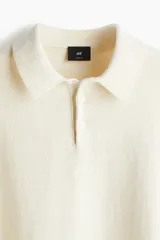 Remera polo de punto fino color crema, de manga larga con puños y bajo acanalados.