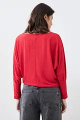 Blusa roja de tejido de punto acanalado, con escote barco y mangas dolman largas.
