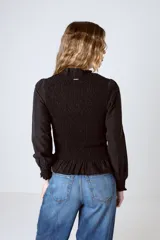 Blusa negra con cuello alto fruncido, mangas largas abullonadas y detalle de volado en el ruedo.