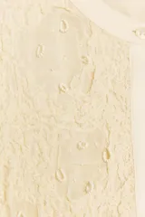 Blusa color crema de viscosa con cuello redondo y manga larga abullonada. Detalle de bordados con aplicación de abalorios y cierre frontal con botones.