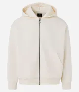 Hoodie con cierre frontal, color crema o blanco roto, de corte boxy y holgado. Presenta capucha con cordón ajustable, bolsillos canguro divididos y puños y cintura acanalados.