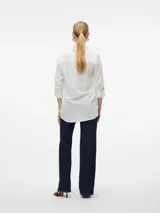Camisa blanca de mangas largas con vuelta, cuello clásico, cierre frontal con botones y dos bolsillos con solapa en el pecho.