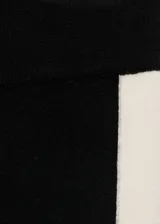 Pantalón de punto fino negro con raya lateral blanca, tiro medio, diseño recto y largo.
