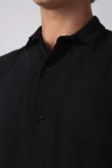 Camisa de lino color blanco, de manga corta, con cuello clásico y cierre frontal con botones.