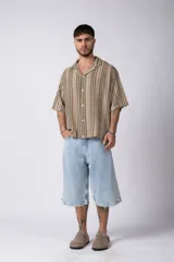 Camisa de manga corta con cuello solapa, corte holgado y estampado de rayas verticales en tonos beige, negro y rojo.