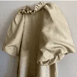 Vestido color beige de lino 100%, con mangas cortas abuchonadas, cuello con volados y calce holgado evasé.