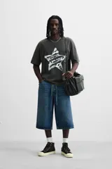 Camiseta negra con efecto lavado, cuello redondo, manga corta y estampado de estrella con texto en el centro.