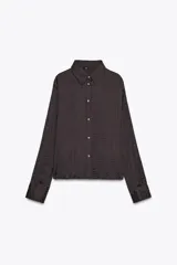 Camisa oversize color marrón oscuro confeccionada en tejido satinado con efecto arrugado, cuello solapa, manga larga con puños y cierre frontal con botones metálicos.