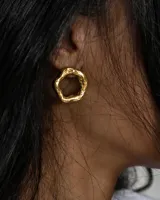 Par de aros dorados con forma de círculo orgánico irregular.