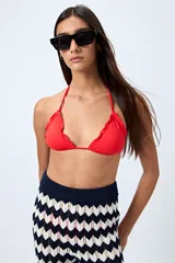 Top de bikini blanco con tirantes finos ajustables al cuello y a la espalda. Presenta volados en el escote y está confeccionado en tejido suave con acabado elástico.