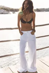 Pantalón de jean blanco, de tiro medio y corte wide leg, con cinco bolsillos y costuras laterales marcadas.
