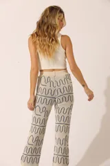 Pantalón de punto color crema con estampado de ondas azules.