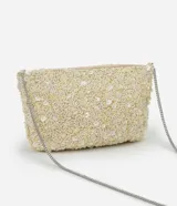 Cartera pequeña transversal color crema, cubierta de lentejuelas y cuentas. Tiene asa de cadena plateada y cierre de cremallera.