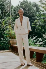Pantalón de vestir color beige, de tiro alto, con cintura elástica en la parte trasera, bolsillos delanteros y falsos bolsillos de vivo en la parte trasera.