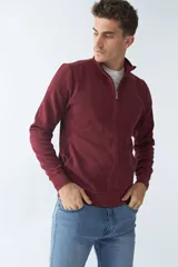 Campera bordó de algodón con cierre frontal, cuello alto, bolsillos laterales, puños y logo bordado en el pecho.